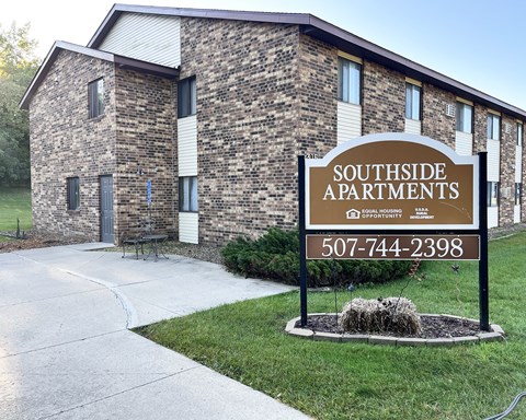 A sign for Southside Apartments is in front of a brick building.
