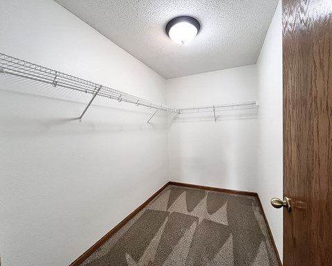 A white wall with a brown rug and a brown door.