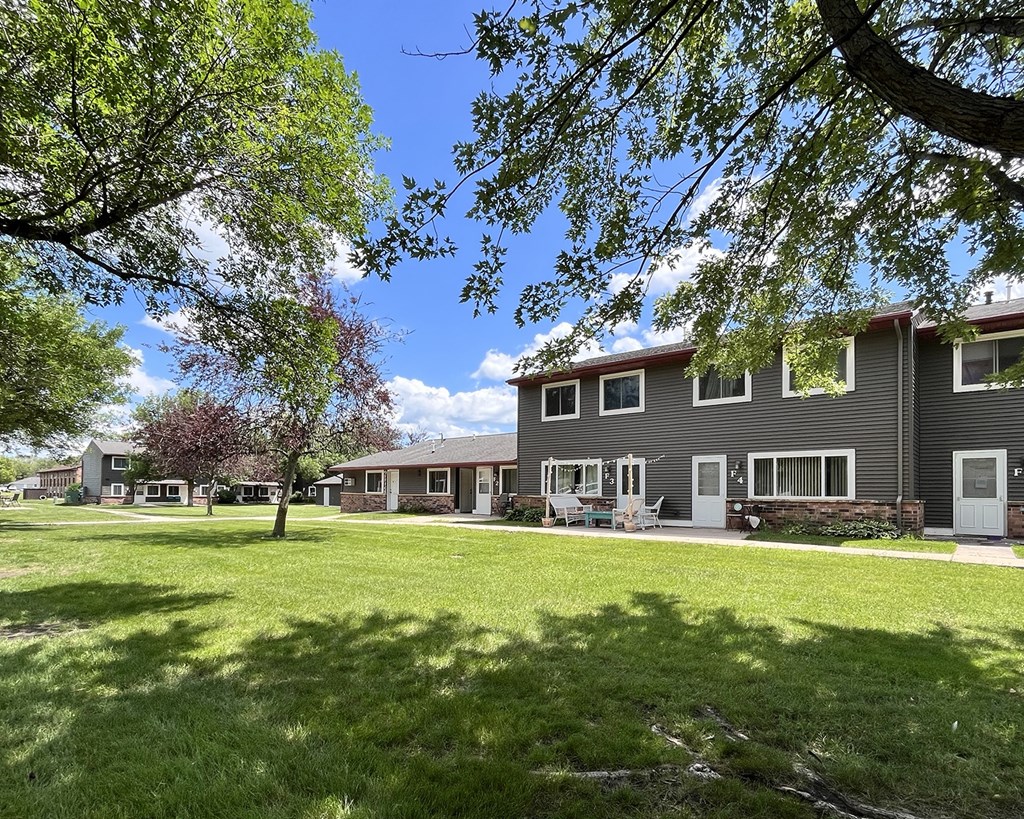 A tree in front of a building with a lawn in front of it.