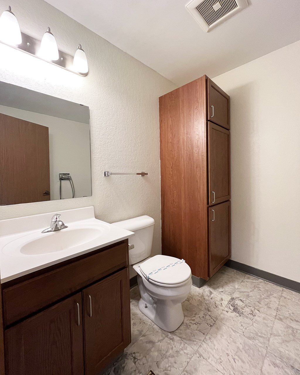 A bathroom with a toilet, sink, and medicine cabinet.
