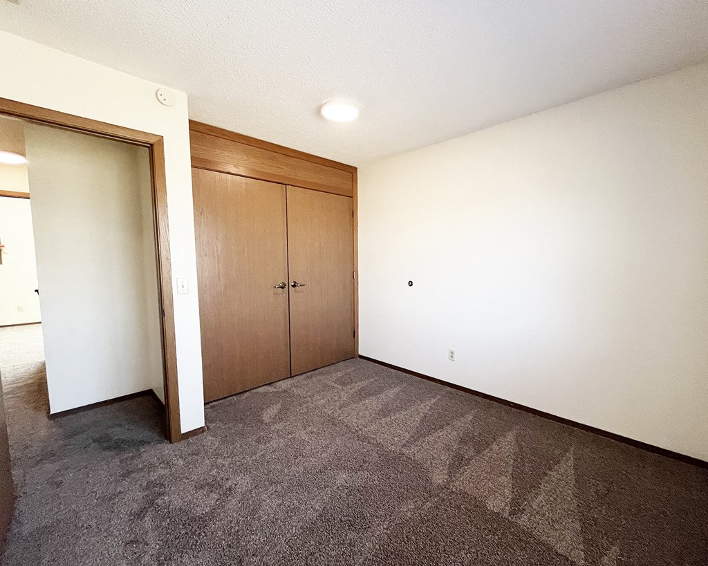 A room with a carpeted floor and a wall-mounted light fixture.
