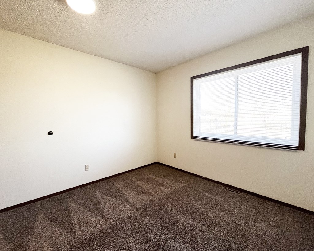 A room with a window and carpeted floor.