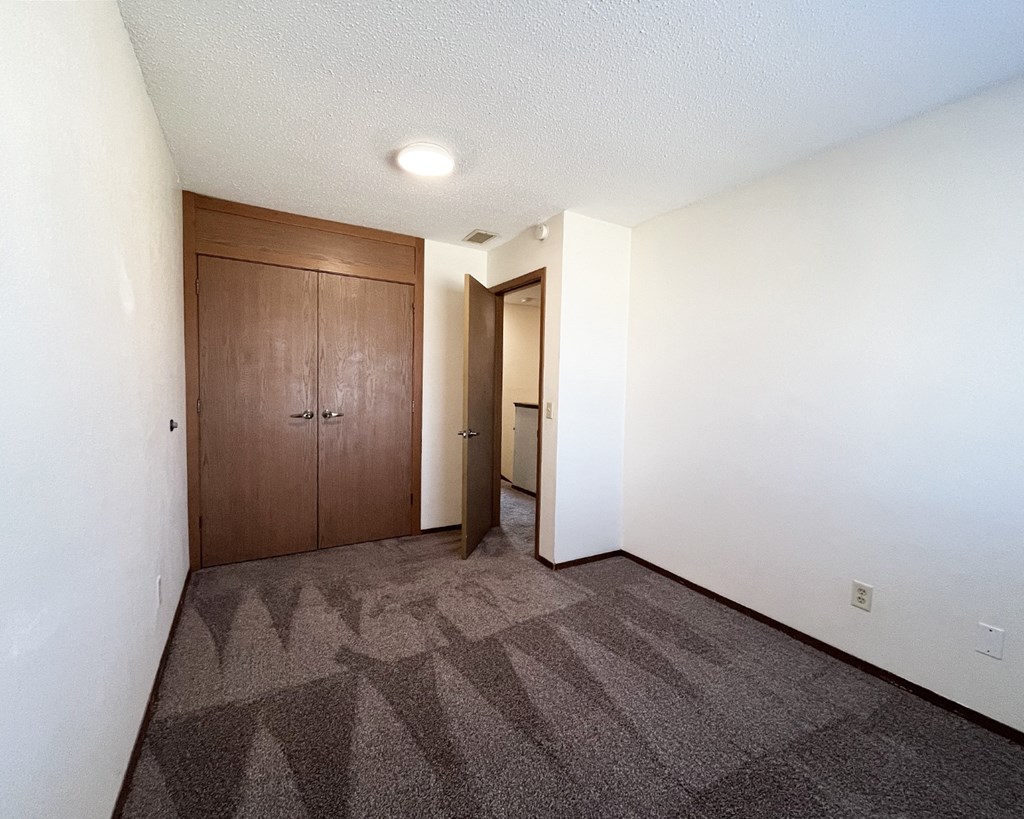 A room with a carpeted floor and a wooden door.