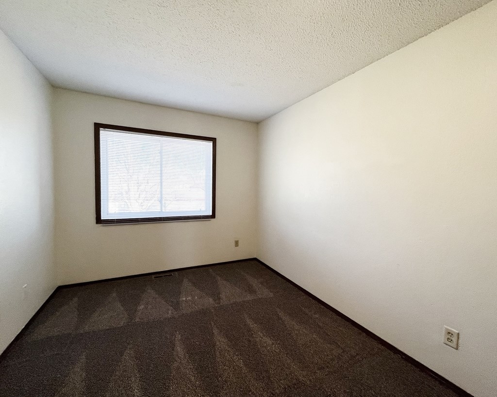 A room with a carpeted floor and a window.