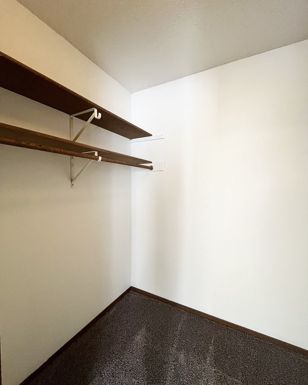 A long hallway with a brown shelf on the wall.