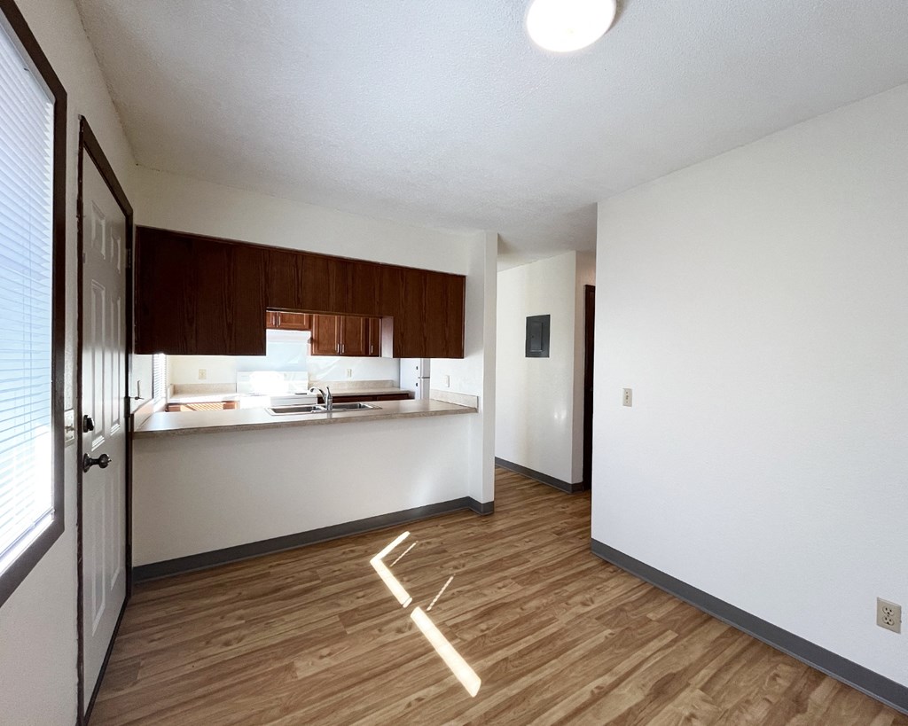 A kitchen with white walls and wooden floors.