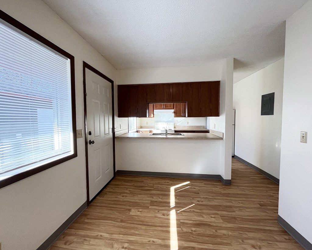 A kitchen with white walls and wooden floors.