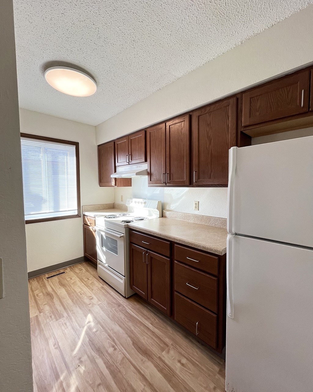 A kitchen with wooden cabinets and a white refrigerator.