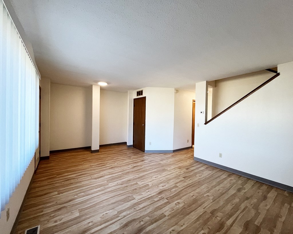 A room with wooden flooring and white walls.