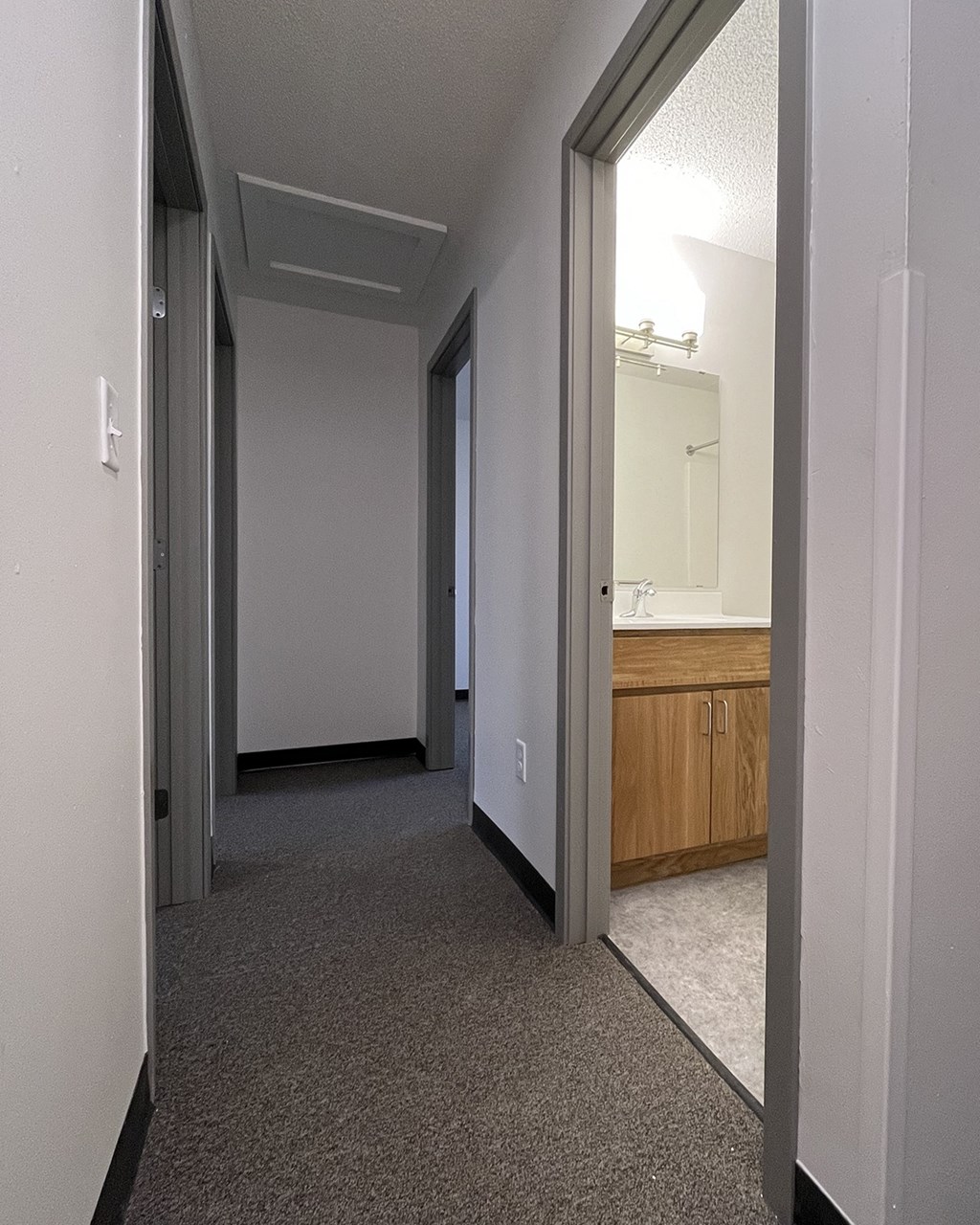 an empty hallway in a home with a bathroom and a sink
