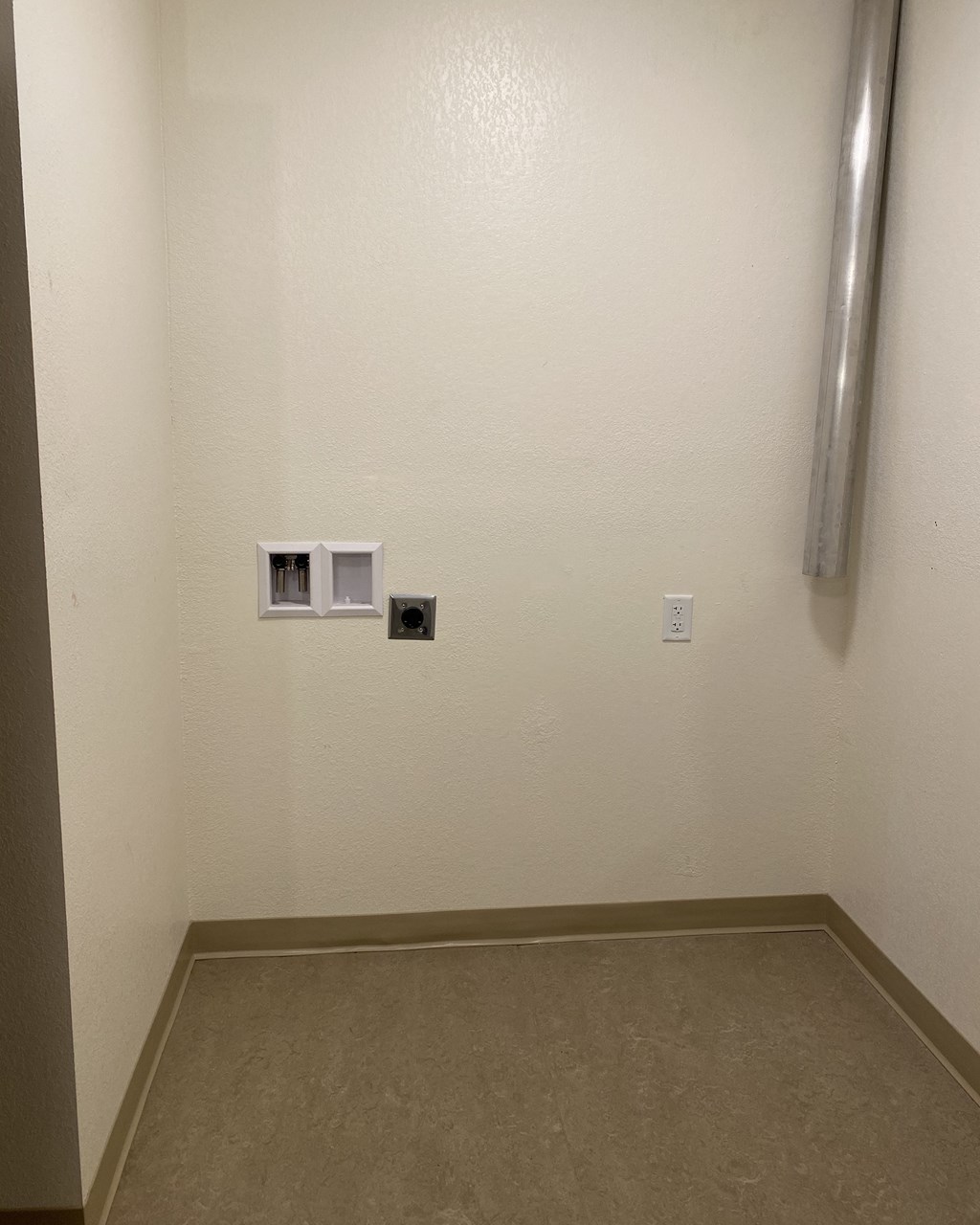 a room with a white wall with two outlets and a pipe