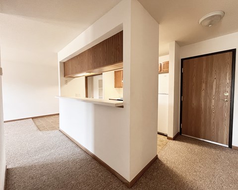 A white kitchen with a brown counter top and a brown door.