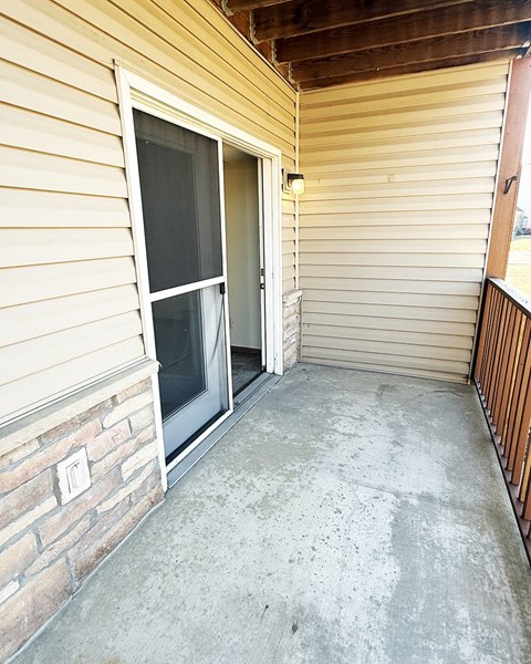 A patio with a sliding glass door and a concrete floor.