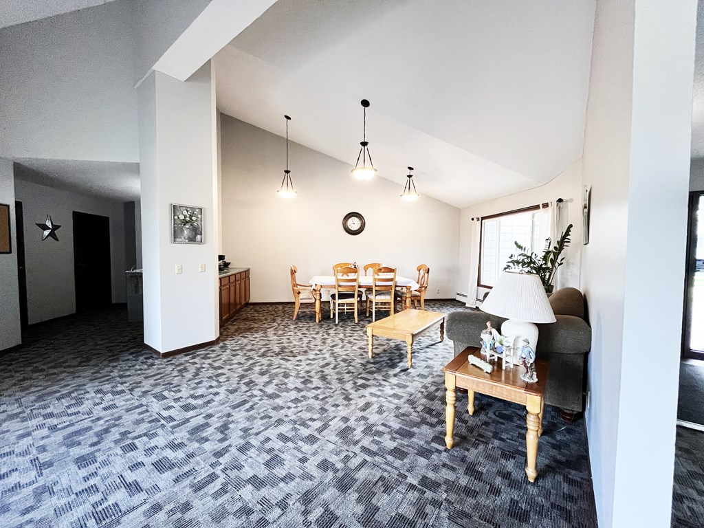 A living room with grey carpet and a wooden table.