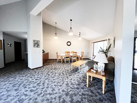 A living room with grey carpet and a wooden table.