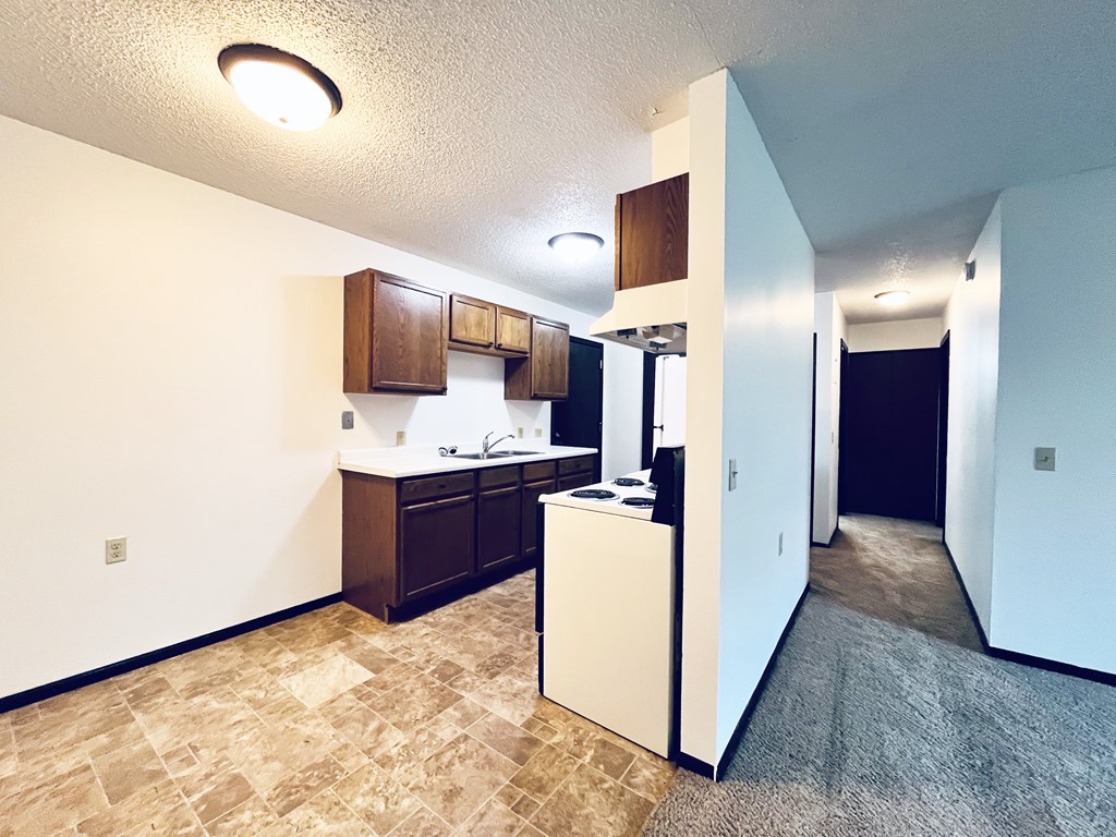 A kitchen with a refrigerator, sink, and cabinets.