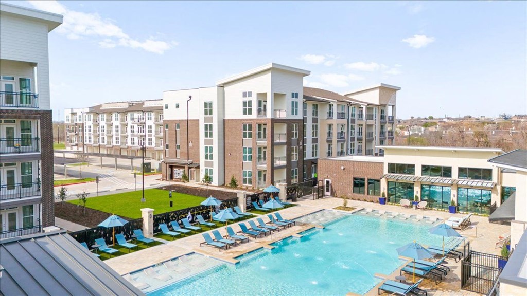 a swimming pool with lounge chairs in front of an apartment building