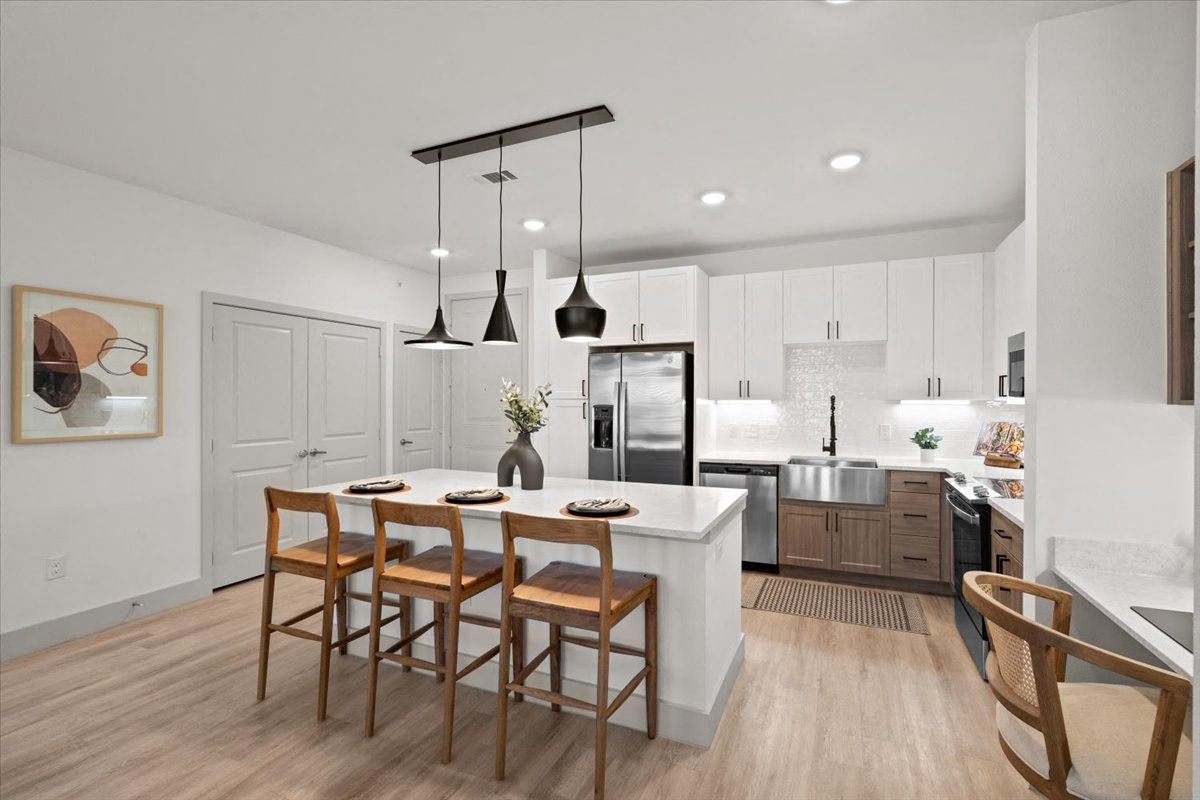 an open kitchen and dining area with a white island and wooden chairs