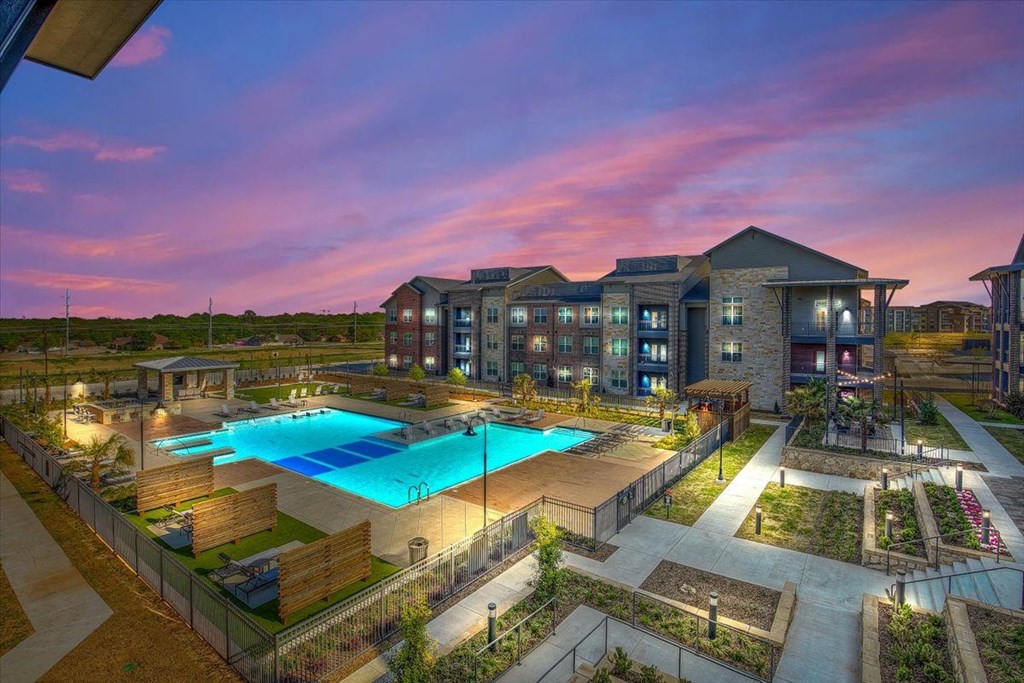 an aerial view of an apartment complex with a pool at dusk