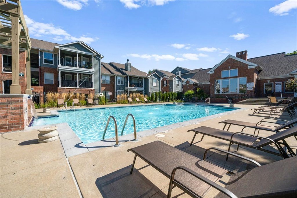 A pool surrounded by lounge chairs and buildings in the background. at Somerset Oaks Apartment Homes, Olathe, KS