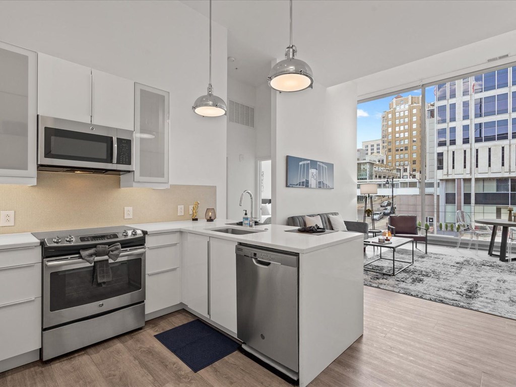 a kitchen with white cabinetry and stainless steel appliances and a large window with a city view at Sky On Main Apartments, Missouri, 64105