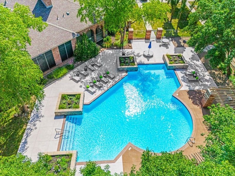an aerial view of a resort style pool with chairs and trees