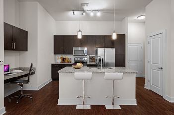 A kitchen with white bar stools and a granite countertop.