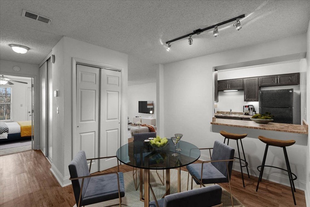a dining room and kitchen with a glass table and chairs at Cloverset Active Adult Apartments, Kansas City, Missouri