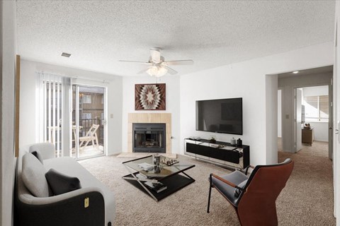 a living room with a ceiling fan and a fireplace at Deerfield Apartments, Kansas