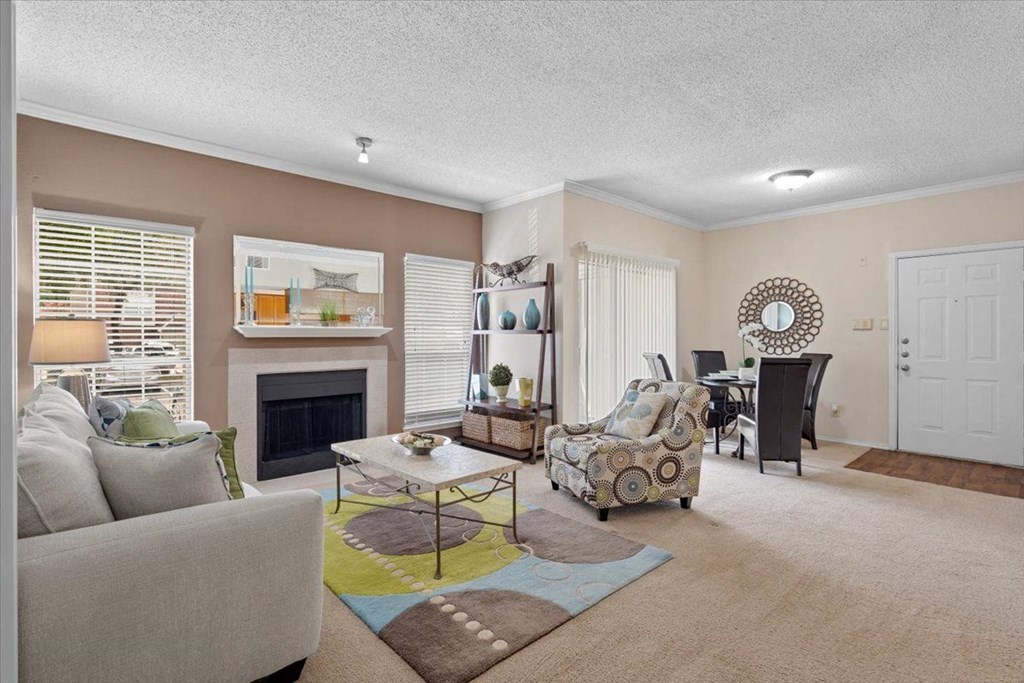 a living room with a fireplace and a dining room in the background at Creekview Apartment Homes, Texas