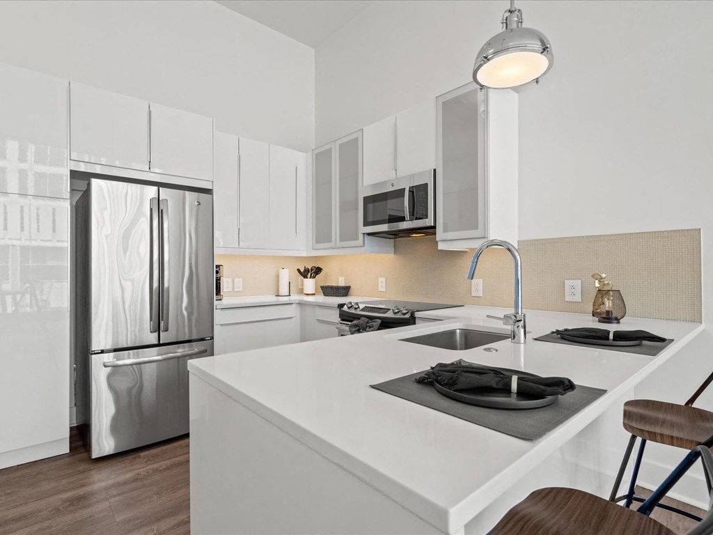 a kitchen with white cabinetry and stainless steel appliances at Sky On Main Apartments, Missouri City