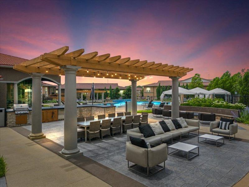 a patio with couches and chairs under a wooden canopy