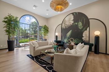 A living room with a large window and a painting on the wall.