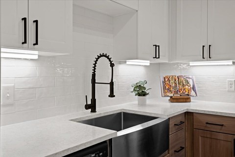 a kitchen with white cabinets and a black sink