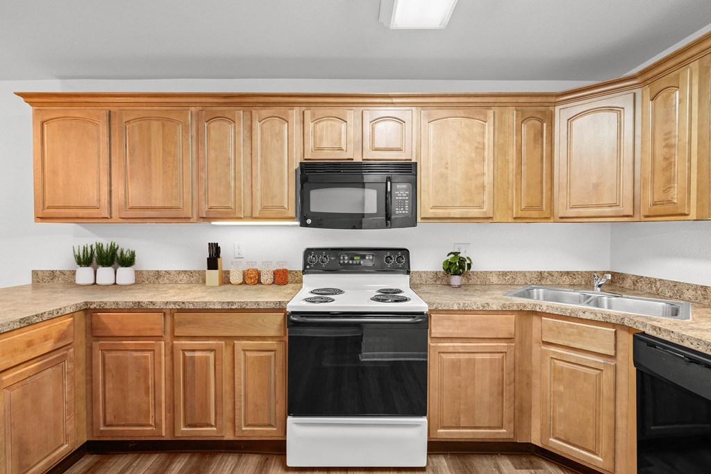 a kitchen with wooden cabinets and a black and white stove top oven at Malvern Hill Apartment Homes, 66103
