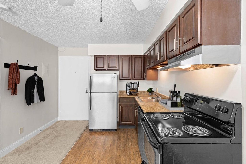 a kitchen with stainless steel appliances and wooden cabinets at Malvern Hill Apartment Homes, Kansas