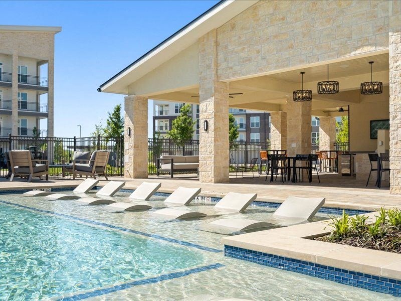 a swimming pool with lounge chairs in front of a building