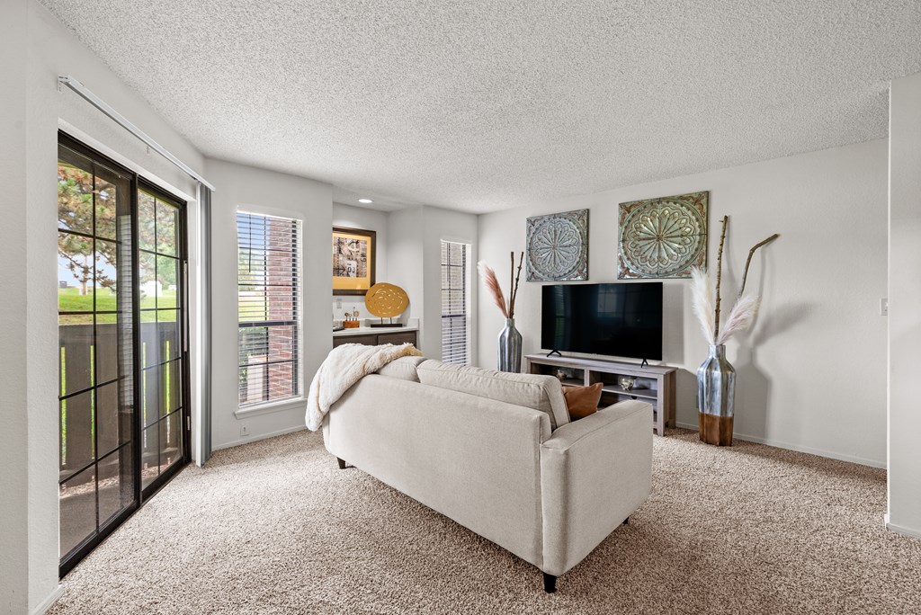 A living room with a white couch and a television. at Coventry Oaks Apartments, Overland Park, KS