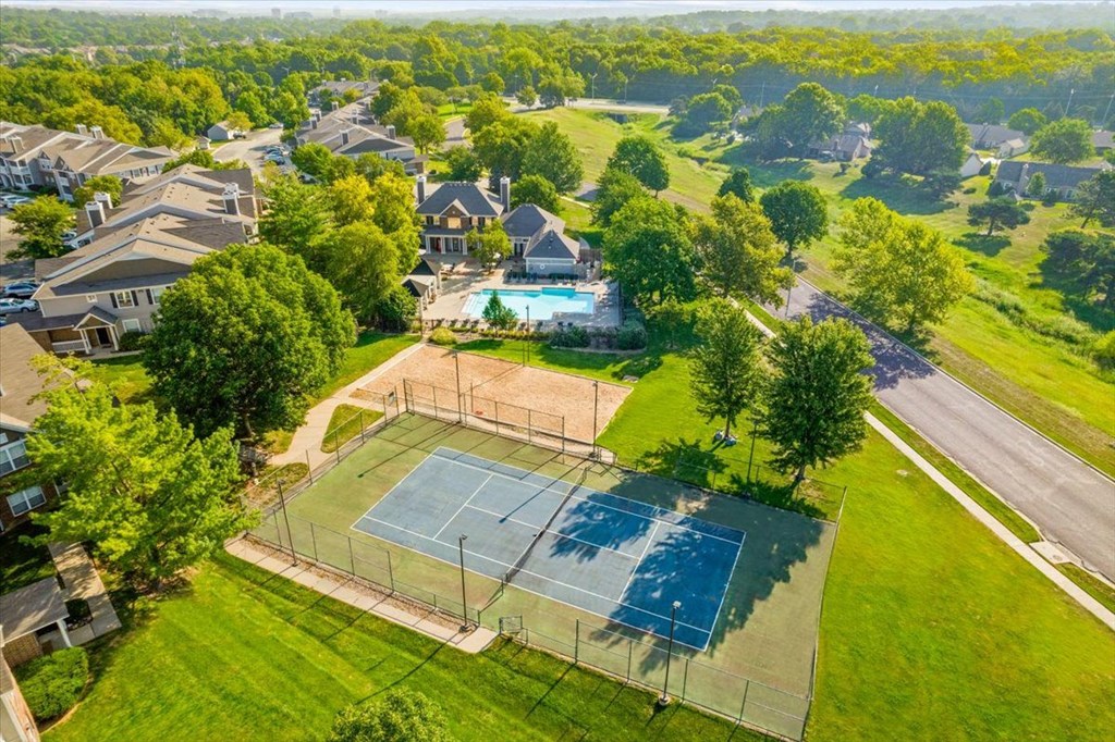 an aerial view of a house with a tennis court in the foreground and a swimming pool inat Stonebriar Woods Apartments, Kansas, 66213
