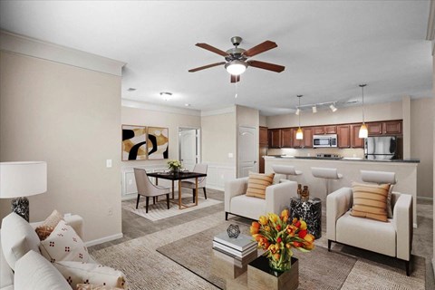 A living room with a dining area, open kitchen, crown molding and ceiling fan.