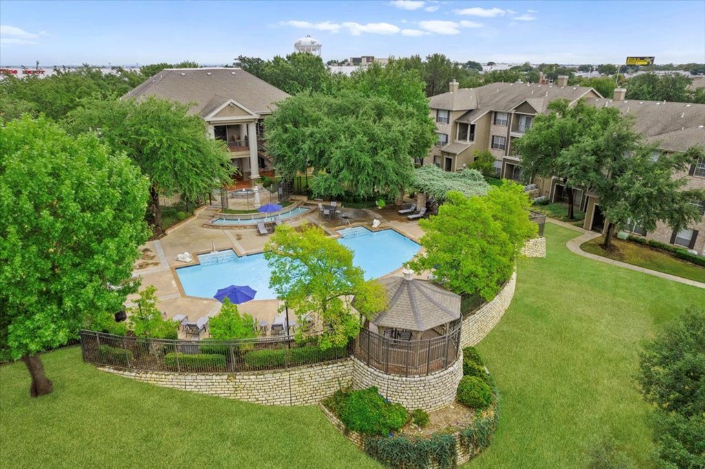 an aerial view of an apartment complex with a large pool in the middle of the yard at The Clairborne Apartment Homes, Grand Prairie