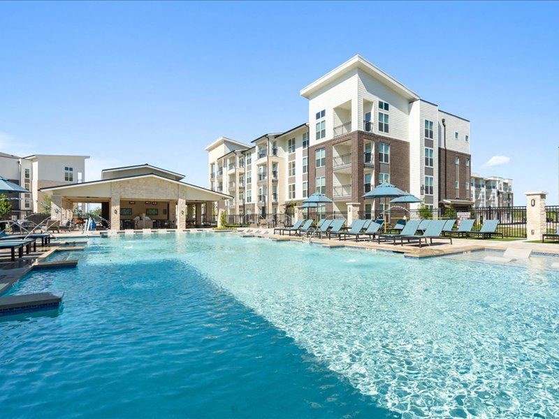 a large swimming pool with lounge chairs in front of a building