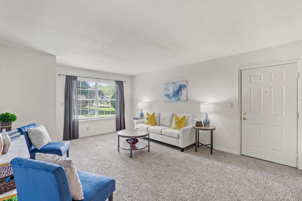 a living room with a white couch and blue chairs and a white door with a gold knob at Pebblebrook, Overland Park, KS