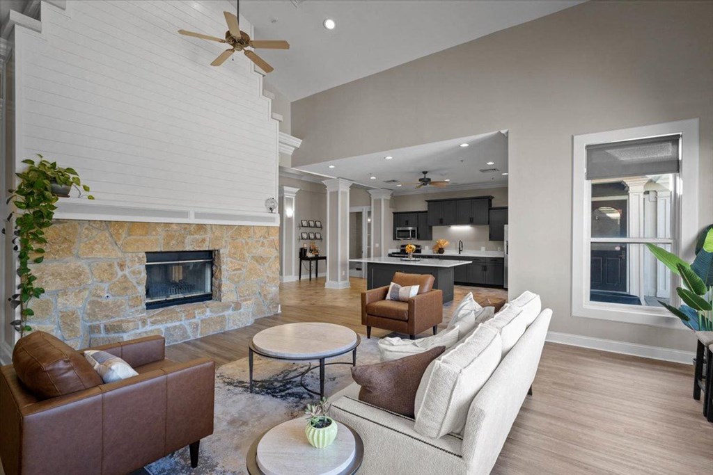A living room with a stone fireplace and a brown leather couch. at Somerset Oaks Apartment Homes, Olathe