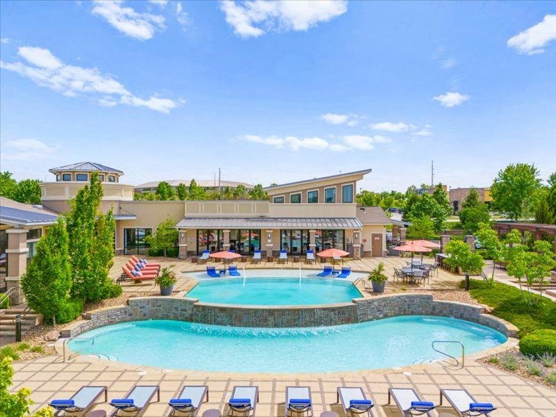 a swimming pool with chairs around it in front of a hotel