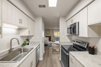 A modern kitchen with a stainless steel sink and oven.