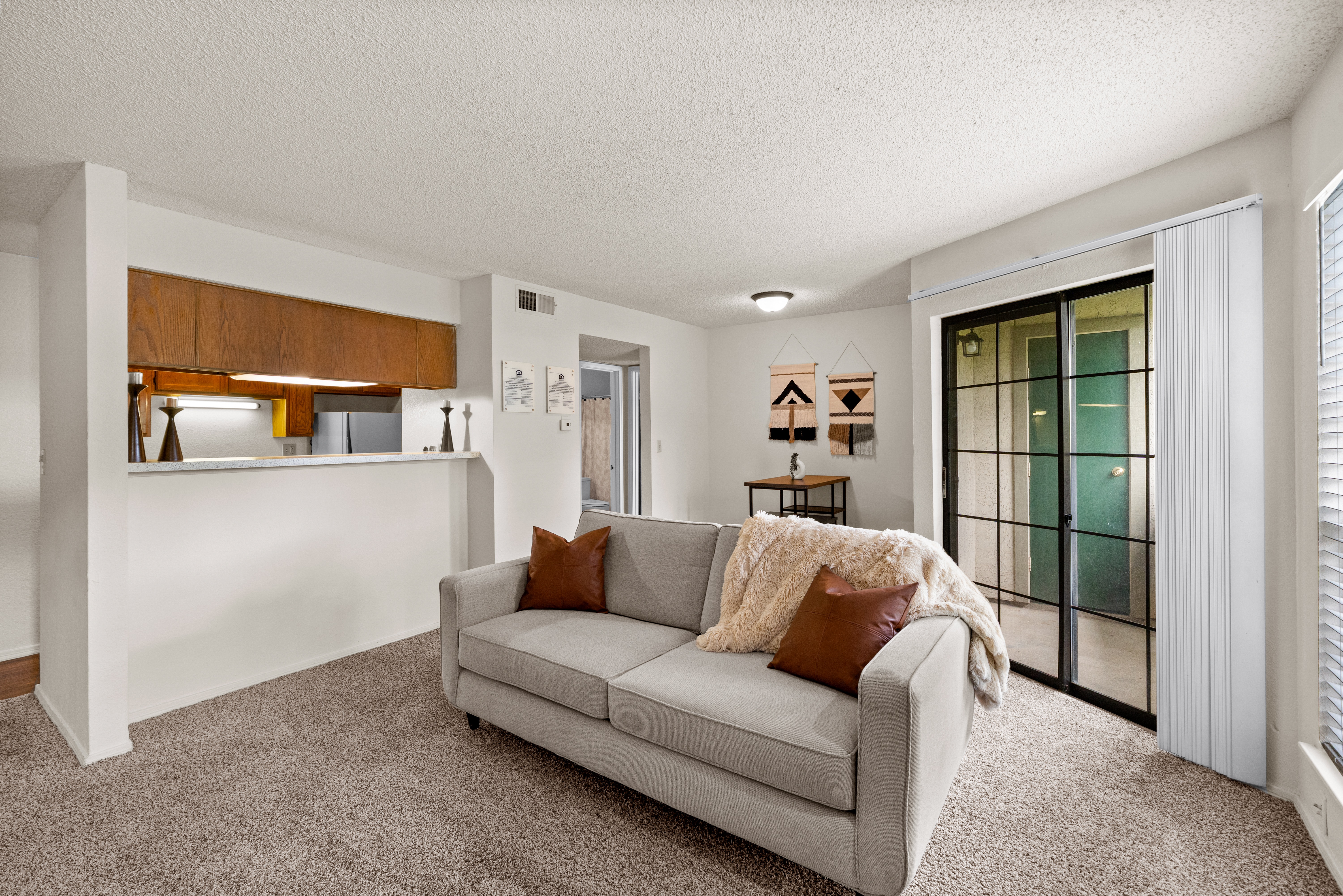 A living room with a grey couch and a wooden cabinet.