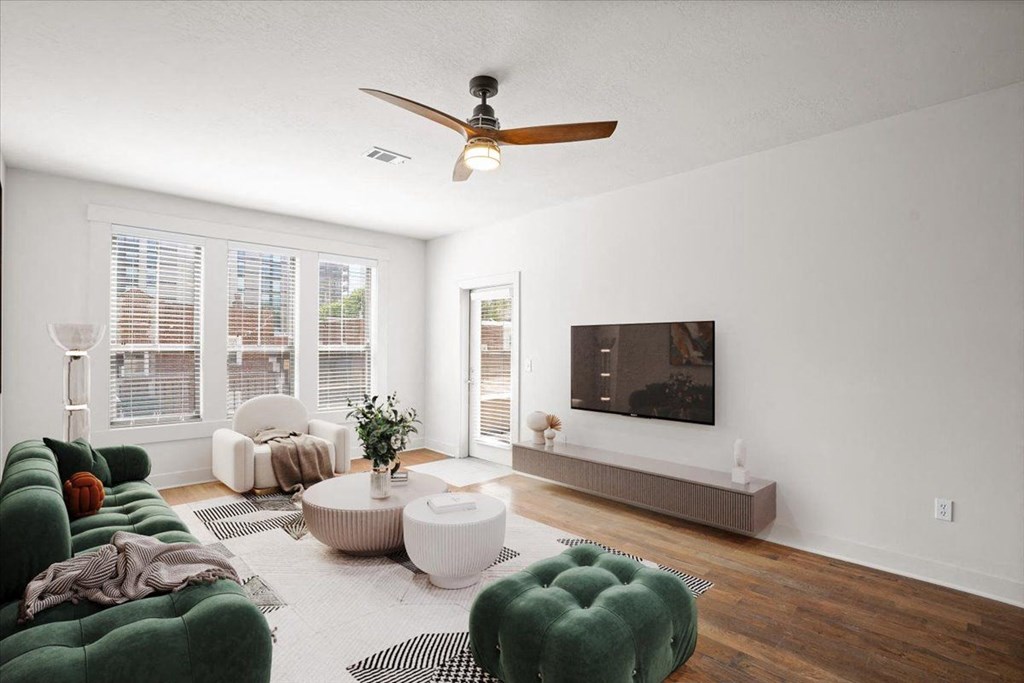 A living room with hardwood floors, a ceiling fan, and windows at Mirabelle Luxury Apartments, Kansas City, Missouri