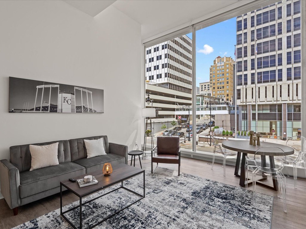 a living room with a large window and a view of a city at Sky On Main Apartments, Missouri, 64105