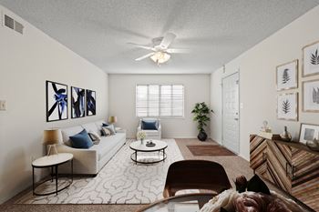 A living room with a ceiling fan and a large window at Bristol Pointe Apartments in Olathe, Kansas.